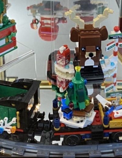 A festive display of Lego Christmas decorations in a glass case.