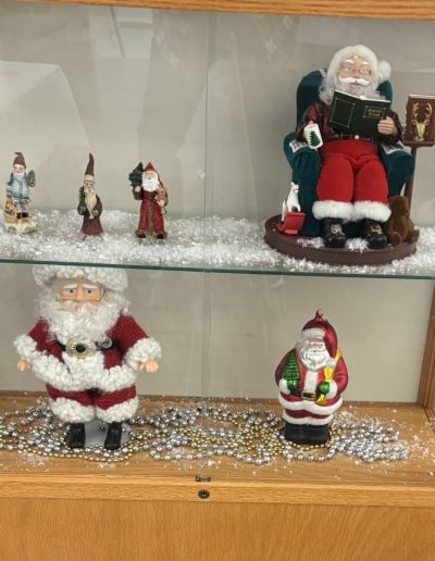 A display case featuring various Santa Claus figurines, showcasing their festive designs and cheerful expressions.