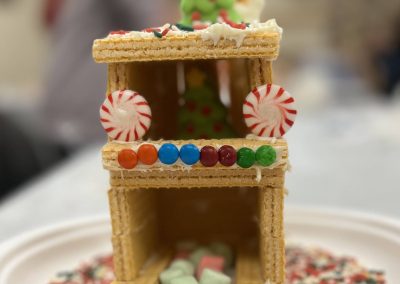 A festive gingerbread house styled as a train, complete with icing details and an array of colorful candy decorations.