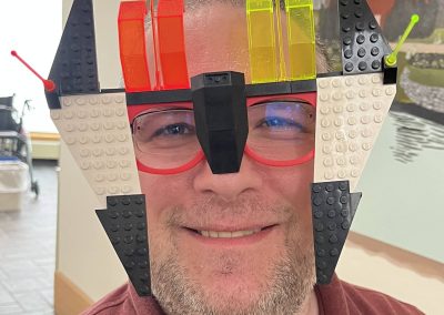 A person wearing LEGO glasses with colorful blocks and antennae.