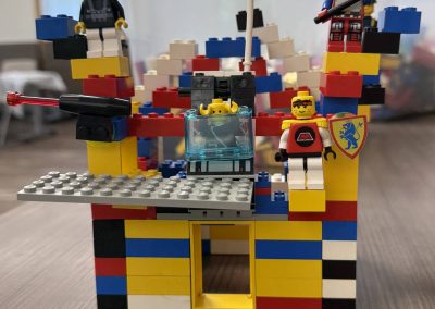 Colorful LEGO structure with minifigures and a cannon on a gray platform.