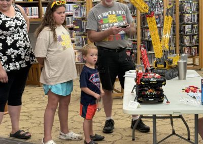 People observing a LEGO crane demonstration at the library.