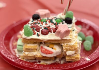 A festive dessert made of wafer cookies and candies on a red plate.