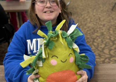 Child holding the finished avocado pillow with a smiley face.