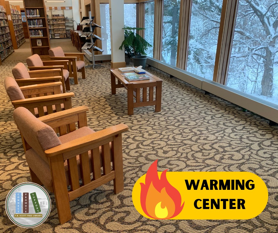 The image shows an interior view of a library space designed with wooden furniture and large windows. In the foreground, five wooden armchairs with fabric cushions are positioned in a row, facing a low wooden coffee table that has several magazines arranged on it. The floor has a patterned carpet with swirling designs. On the right side, large windows stretch along the wall, providing a view of snow-covered trees outside. In the background, bookshelves filled with books and a standing plant are visible. At the bottom left is a circular logo, and in the bottom right corner, there is a yellow rectangle with a stylized flame and the words "WARMING CENTER" in bold text.